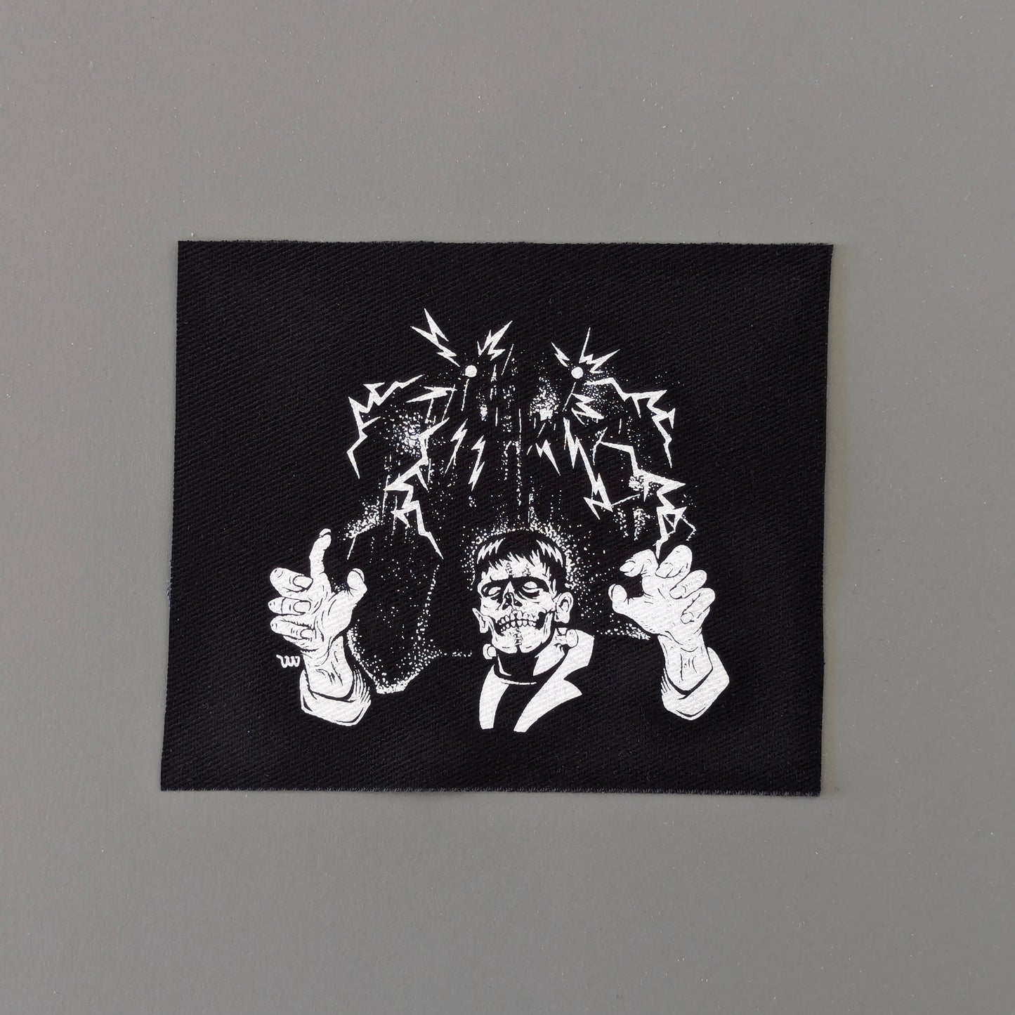 Black square patch with white graphic design on a gray background