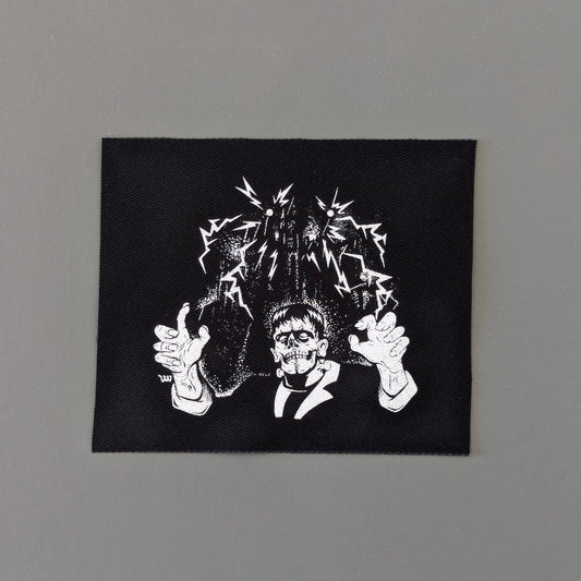 Black square patch with white graphic design on a gray background