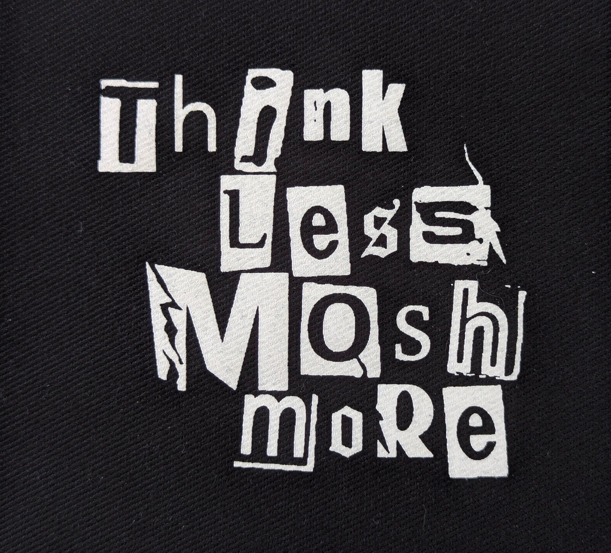 Black patch with white text, punk-style font 'Think Less Mash More' on a textured black background