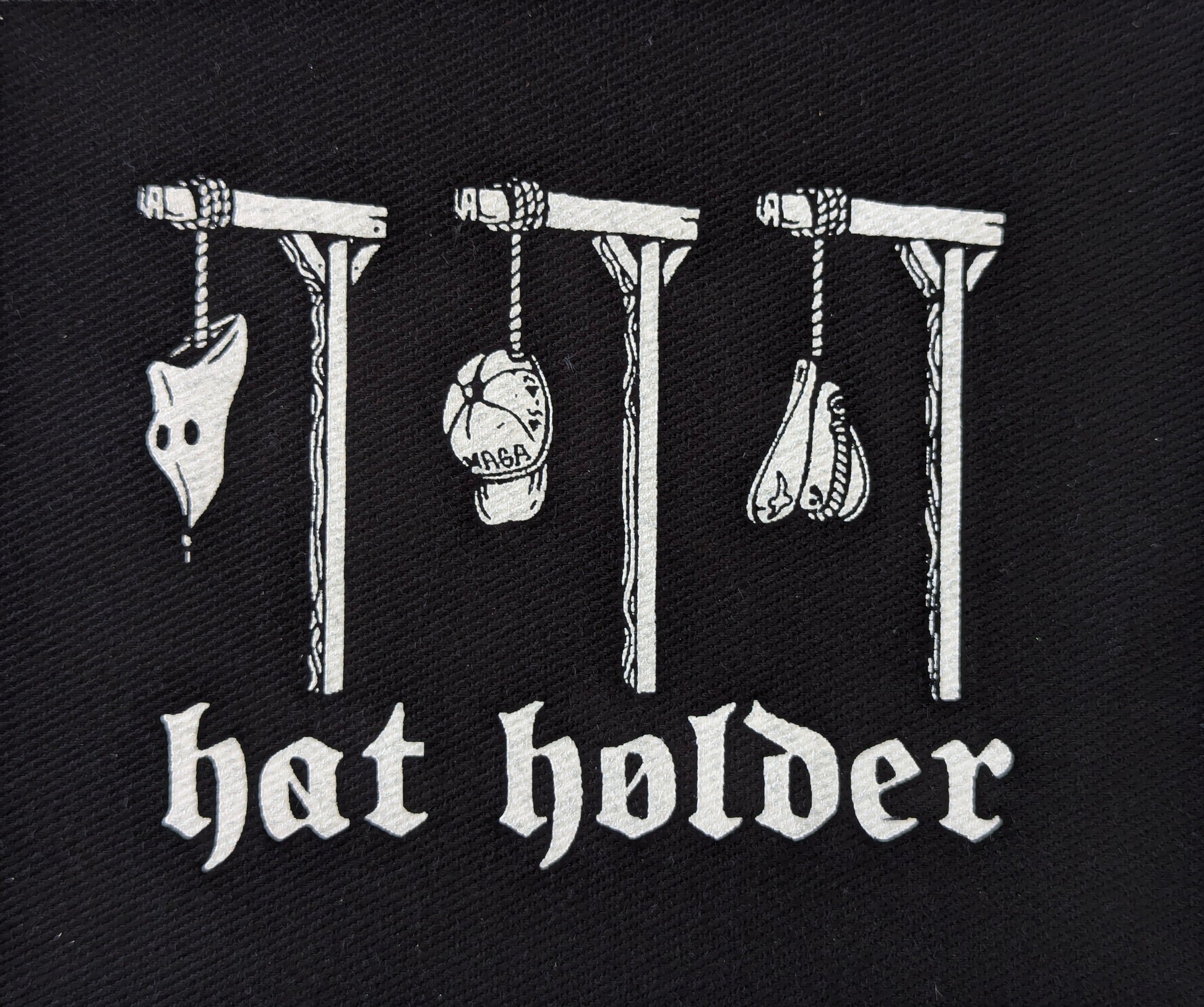 Black patch with white text and illustrations of hats on hooks, labeled 'hat holder'.